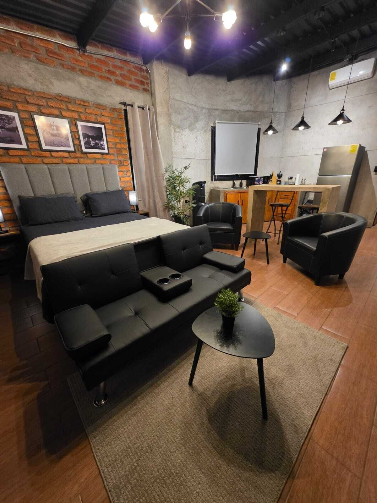 Una habitación moderna y funcional con cama, sofá, escritorio y zona de estar.