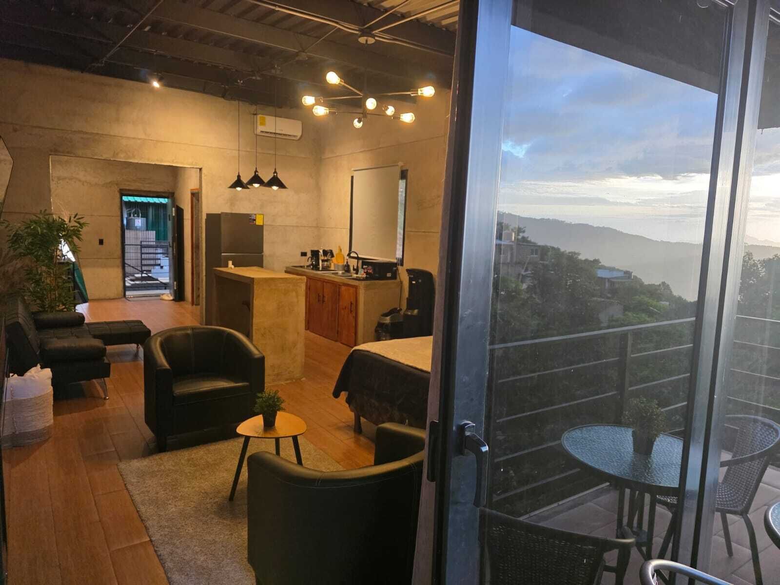 A modern interior with a kitchen, seating area, and a balcony with a view.
