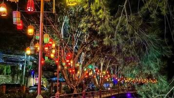 A bridge with colorful lanterns and lights, surrounded by trees.
