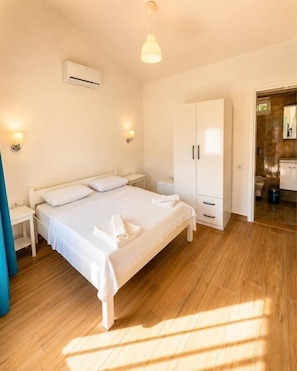 A bedroom with a bed, bedside tables, a wardrobe, and an air conditioning unit. - Doğa pansiyon (muğla)