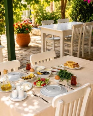 A table set for a meal with plates, bowls, and a bottle of olive oil. - Doğa pansiyon (Marmaris)