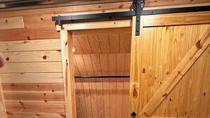 Een kamer in boerderijstijl, met een grote schuifdeur, houten latten in het plafond en een visgraatvloer.