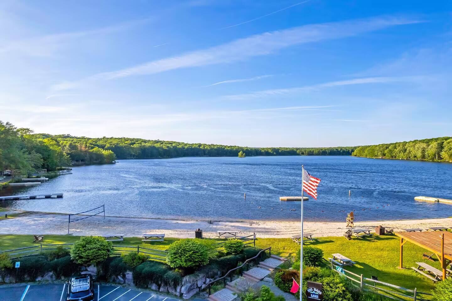 Blick auf einen See mit einem Steg, Picknicktischen und einer amerikanischen Flagge.