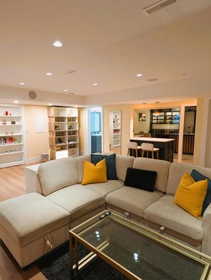 A modern living room with a sectional sofa, glass coffee table, and built-in shelving. - Cozy and Chic unit with wine cellar. (Maple Ridge)