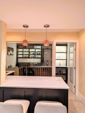 Une cuisine moderne dotée d’un îlot central, de luminaires suspendus et d’un meuble à vin.