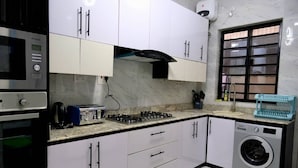 A kitchen with a gas stove, a washing machine, and a toaster. - Perfect 4-bedroom apartment with Starlink and 24/7 Inverter Power in Lekki (Lekki)