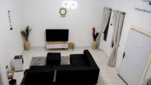 A living room with a TV, sofa, and a small table. - Perfect 4-bedroom apartment with Starlink and 24/7 Inverter Power in Lekki (Lekki)