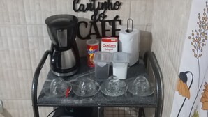 Una encimera de cocina con una cafetera, un cartón de Godam Integral, un recipiente rojo y vasos de plástico.