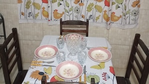 Una mesa de comedor con mantel floreado, sillas y cristalería.