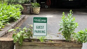 A welcome sign for guest parking, surrounded by potted plants and a wooden planter. - Spacious 1-bedroom suite surrounded by nature in charming Downingtown. (Downingtown)