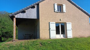Un bâtiment à deux étages doté d’un patio couvert, d’une porte-fenêtre coulissante et d’une petite table.