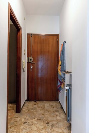 A hallway with a wooden door, a telephone, and a radiator. - Appartamento Magnolia - Affitti Brevi Italia (Borghetto Santo Spirito)