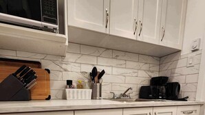 A kitchen with white cabinets, a microwave, a coffee maker, and a knife block. - Montreal Rental 2 BRs/ Full Bathroom (Montréal)