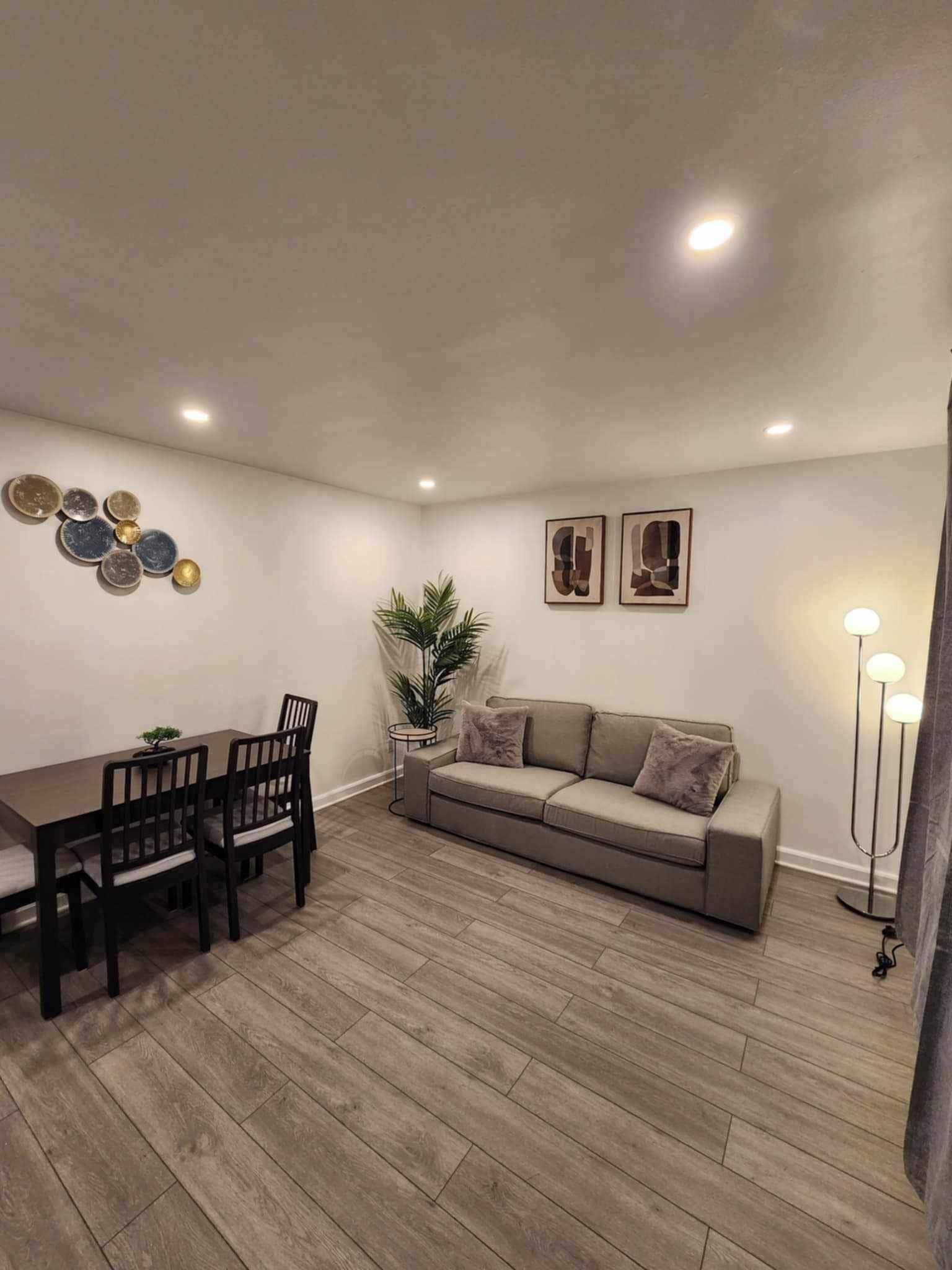 Un salon comprenant une table à manger, des chaises, un canapé, une lampe sur pied et des œuvres d’art murales.