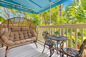A covered outdoor area with a wicker sofa, metal chairs, and a small table. - Turtle Nest Condo + Pool / 2nd Floor (Key West)