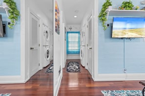 A laundry room with a washing machine, dryer, and a blue door. - Turtle Nest Condo + Pool / 2nd Floor (Key West)