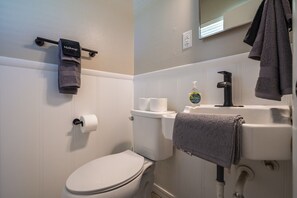 Ein Badezimmer mit Toilette, Waschbecken, Handtuchhalter und Spiegel.