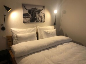 Ein Bett mit weißer Bettwäsche, einem Kopfteil und zwei Nachttischlampen.