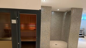 Et moderne interiør med sauna, fliserede vægge og en træbænk.
