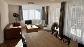 En moderne stue med sofa, spisebord, fjernsyn og en stol.