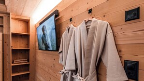 Un intérieur en bois avec un téléviseur fixé au mur, des étagères en bois et un porte-peignoirs.