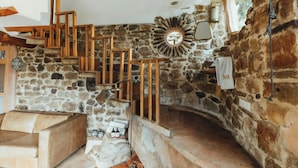 A stone staircase with wooden railings, a stone wall with a circular mirror, and a towel hanging on the wall.