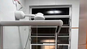 Una habitación con ventana, pared blanca y un dispositivo en el techo.