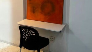 Una habitación con una pared blanca, una silla negra y una mesa blanca.