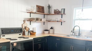 Une cuisine équipée d’une cuisinière, d’un four, de meubles de rangement en bois et d’une fenêtre.