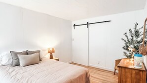 Une chambre à coucher comprenant un lit, une table de chevet, une lampe, une commode, un miroir et une plante.
