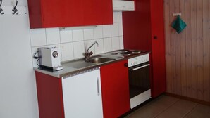 Una cucina con pensili e basi rossi e bianchi, un fornello e un lavello.