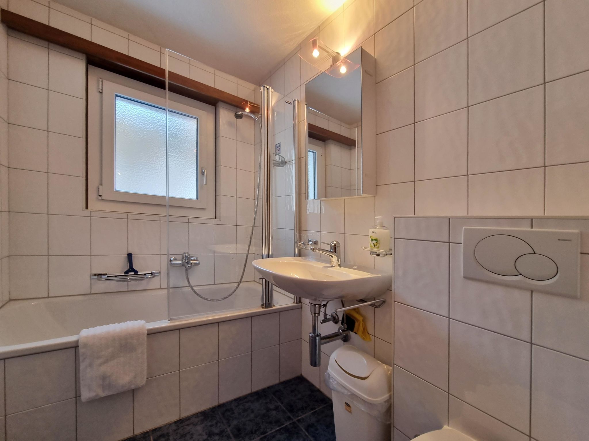 A modern bathroom with a bathtub, sink, and toilet.