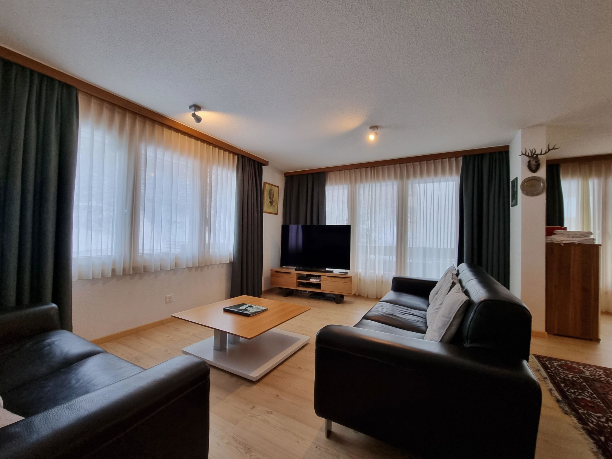 A living room with a sofa, a coffee table, a TV, and curtains.