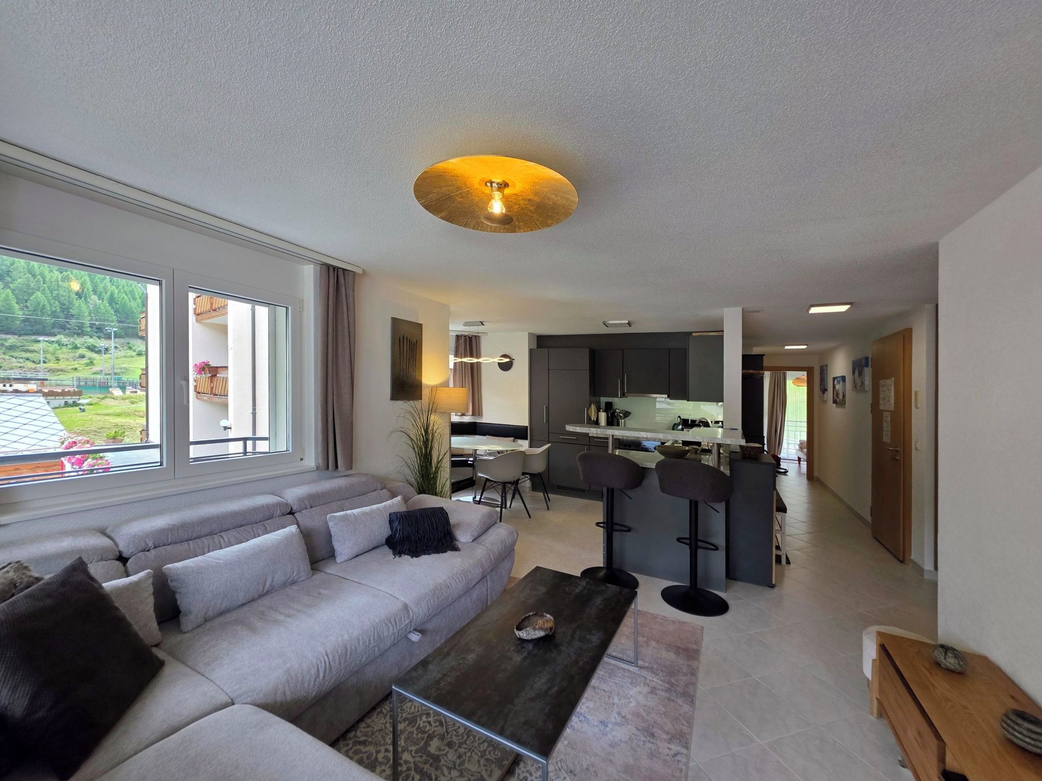 Ein modernes Wohnzimmer mit Sofa, Couchtisch und Blick auf eine Küche und einen Essbereich.