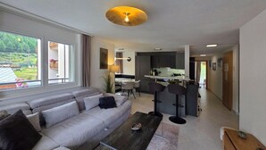 A modern living room with a sofa, a coffee table, and a view of a kitchen and dining area. - Nicoletta 2. OG Appartement/Fewo 8-Bettwohnung Nr. 1 by Interhome (Saas-Fee)