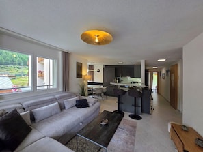 Ein modernes Wohnzimmer mit Sofa, Couchtisch und Blick auf eine Küche und einen Essbereich.