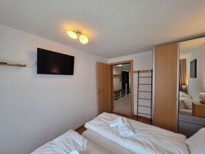 Ein Hotelzimmer mit einem Bett, einem Fernseher, einem Kleiderschrank und einem Spiegel.