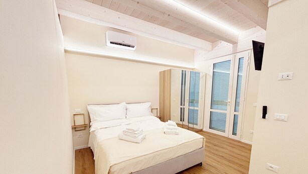 Ein Schlafzimmer mit einem Bett, einem Nachttisch, einer Klimaanlage und einer Tür mit Fenster.