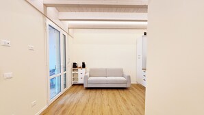 Ein modernes Zimmer mit Holzboden, einer weißen Couch, einem Couchtisch und einem Kleiderschrank.