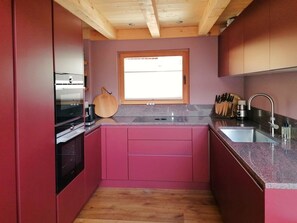 Eine kleine Küche mit Fenster, Holzbalkendecke und einem modernen Waschbecken.