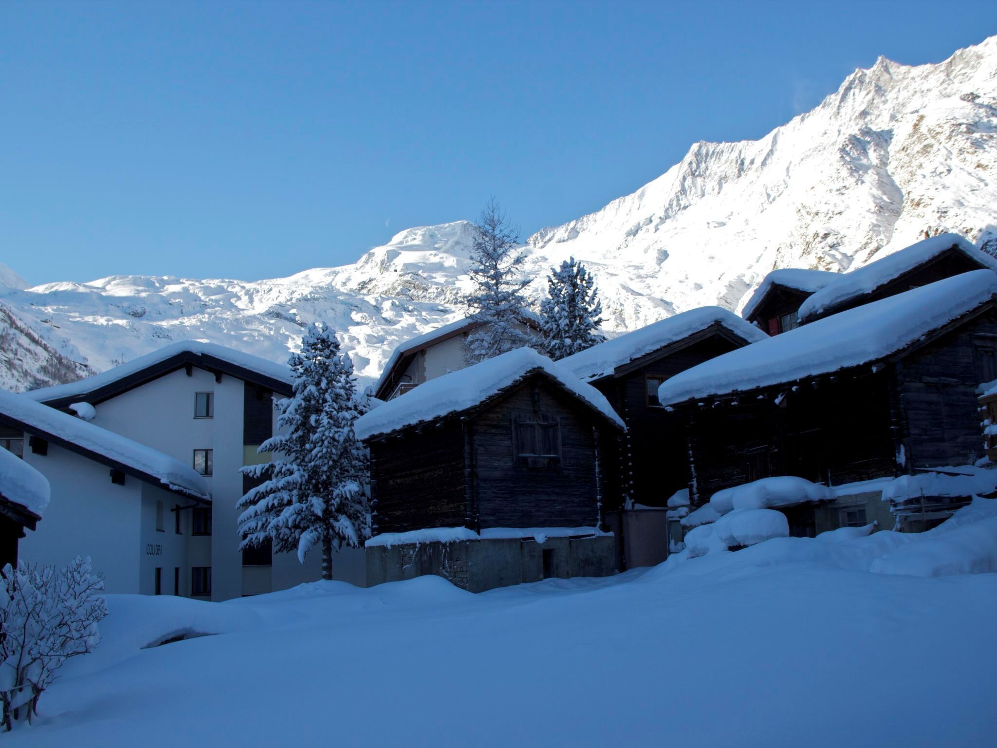 Un pueblo cubierto de nieve con casas de madera tradicionales y una vista despejada de las montañas al fondo.