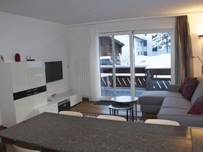Ein modernes Wohnzimmer mit einer Couch, einem kleinen Tisch und einem an der Wand befestigten Fernseher.