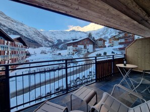 Een balkon met uitzicht op besneeuwde bergen en een rivier.