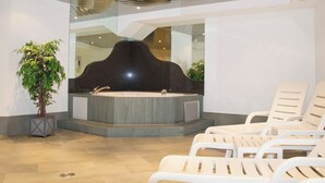 Ein Wellnessbereich mit einer großen schwarzen Badewanne, einem Blumentopf und weißen Liegestühlen.