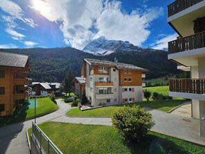 A multi-story building with balconies, a green lawn, and a mountain in the background. - Dominic B1 03 Appartement/Fewo 6-Bettwohnung by Interhome (Saas-Fee)