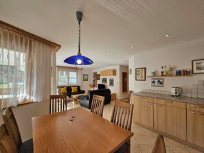 A modern kitchen with wooden cabinets, a dining table, and a kitchen island. - Dominic B1 03 Appartement/Fewo 6-Bettwohnung by Interhome (Saas-Fee)