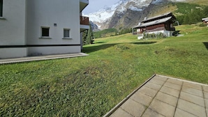 Ein Gebäude mit Balkon, einem Rasen und einem Berg im Hintergrund.