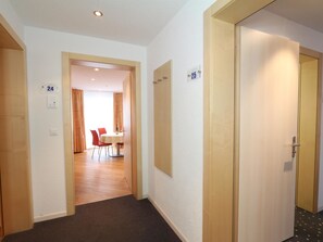 Ein Hotelgang, durch eine geöffnete Tür ist ein Essbereich sichtbar, mit einem Tisch und Stühlen.