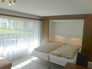 A bedroom with a bed, a desk, and a chair. There is a window with curtains. - Alouette Appartement/Fewo 6-Bettwohnung Nr. 13 by Interhome (Saas-Fee)