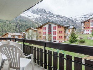 A balcony with a view of a mountainous landscape, wooden buildings, and a chair. - Alouette Appartement/Fewo 6-Bettwohnung Nr. 13 by Interhome (Saas-Fee)
